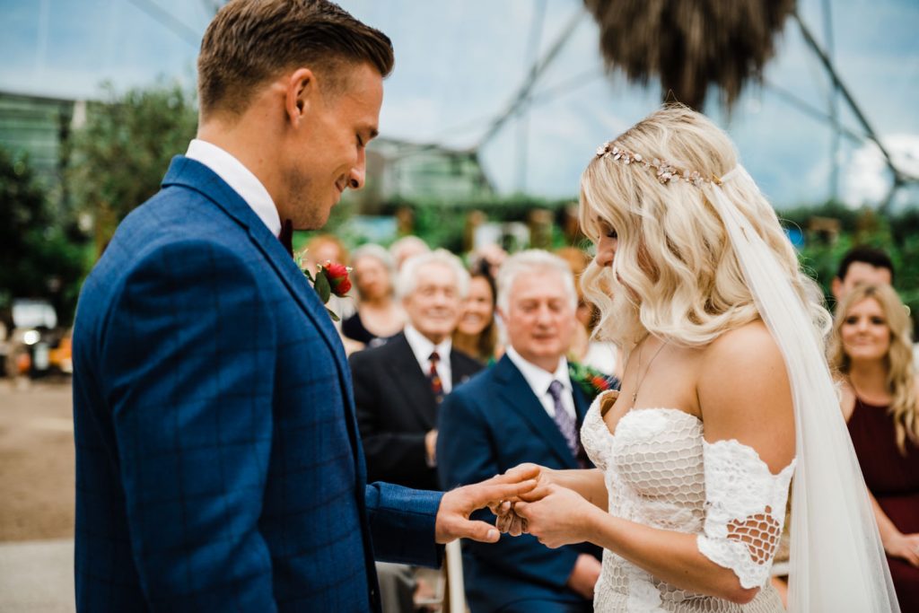 Bride puts wedding ring on grooms finger