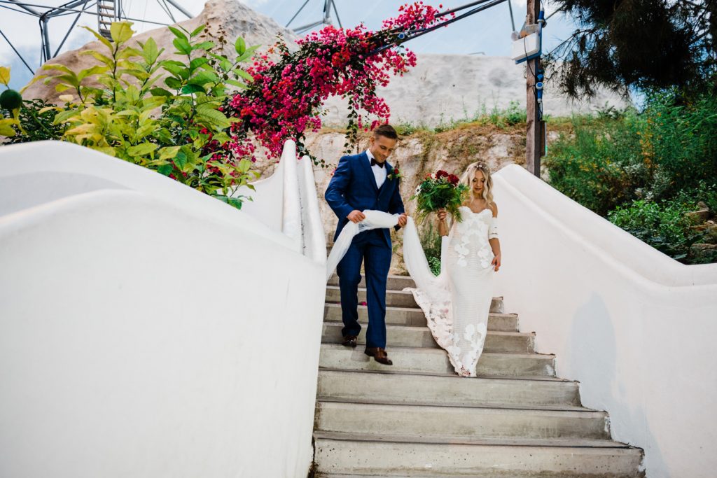 Bride and groom walk down steps in Eden Project