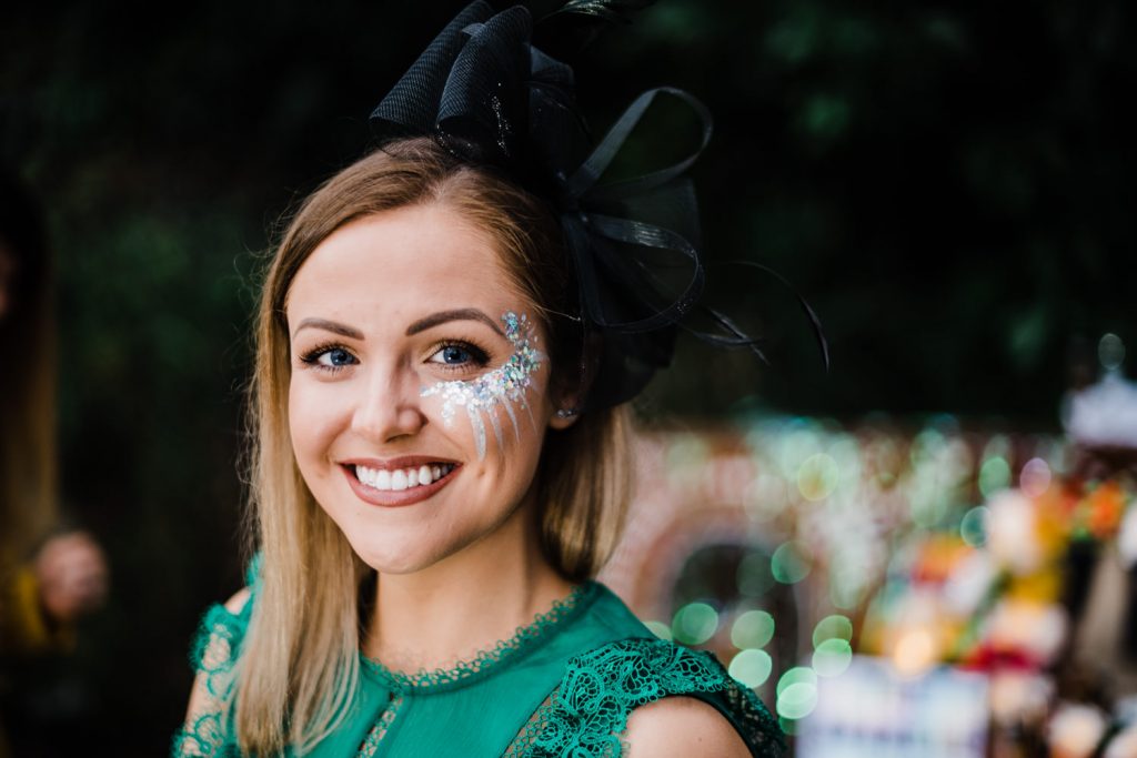 Wedding guest smiles for camera with glitter paint on cheek