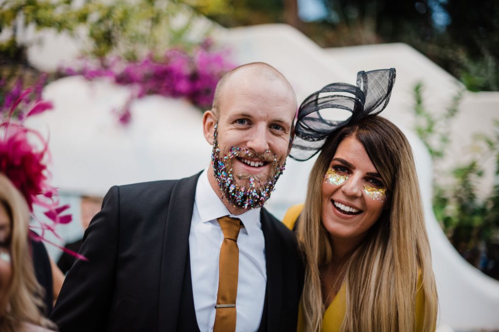 Wedding guests pose with glitter beard and face glitter.