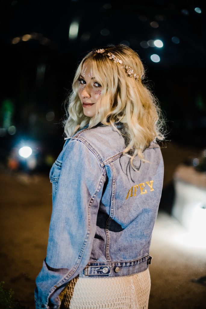 bride poses for camera with 'wifey' denim jacket.