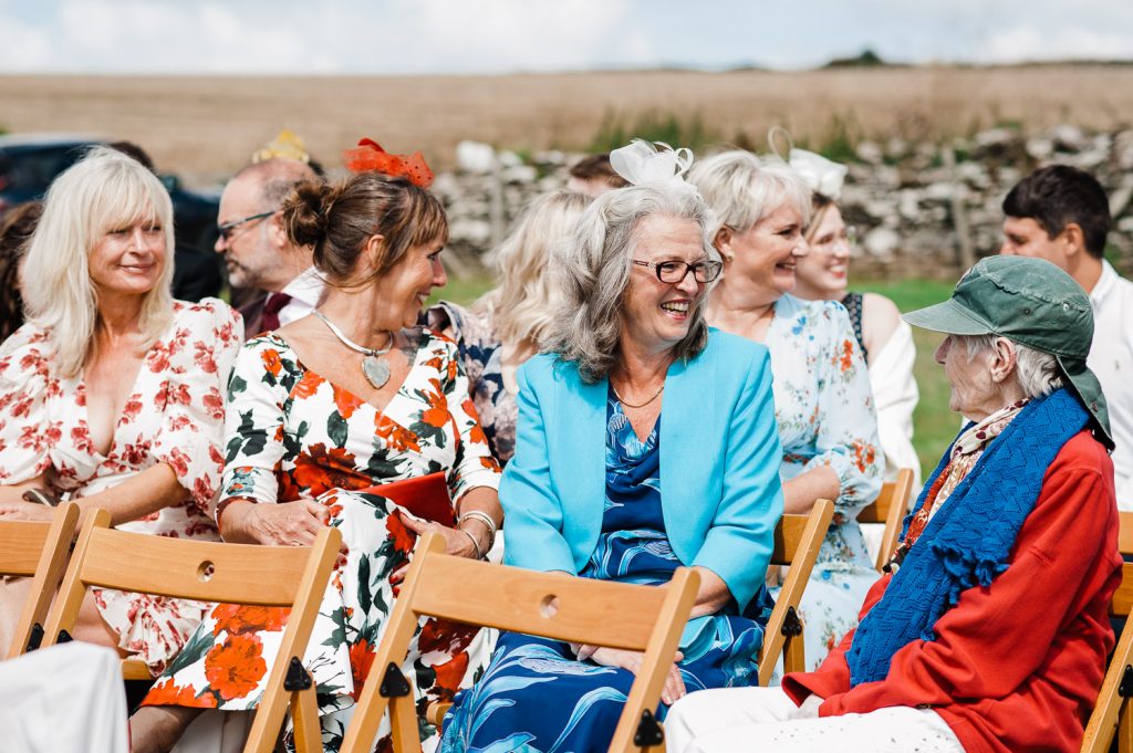 Guests laughing whilst seated outdoors.