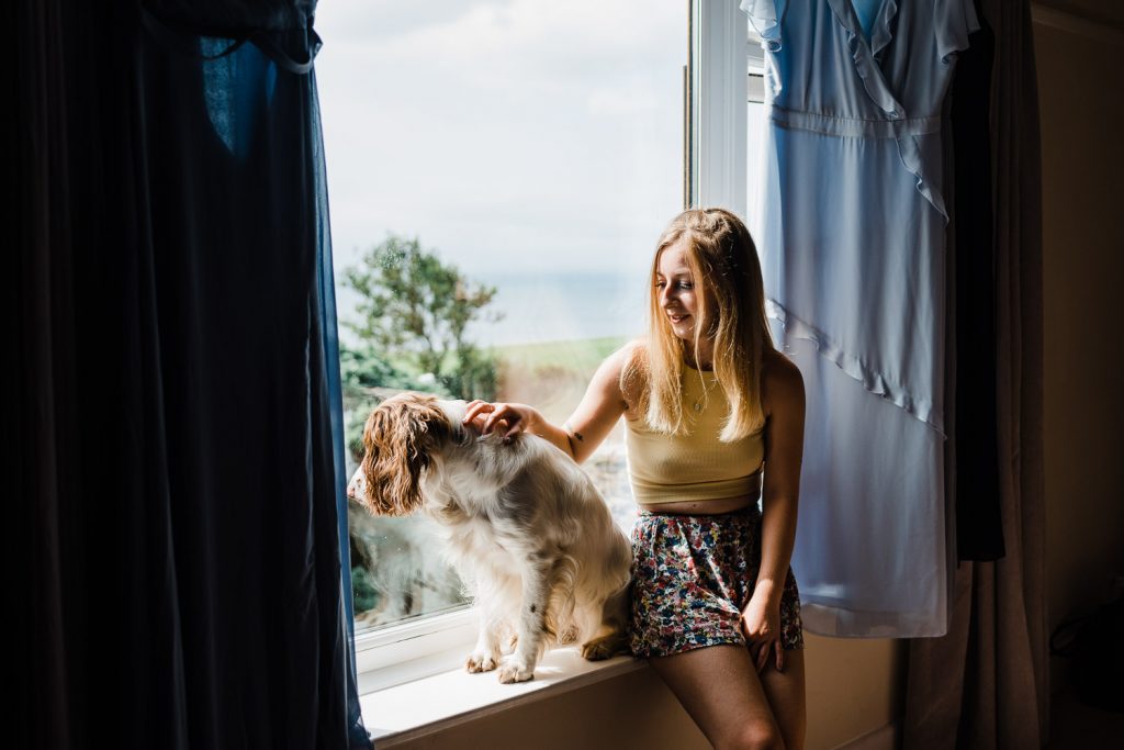 Groom's sister and dog sitting on window sill.