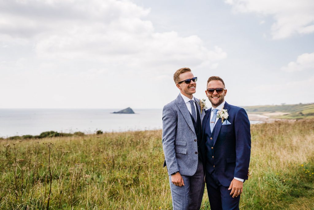 Grooms pose smiling in front of the Mewstone.
