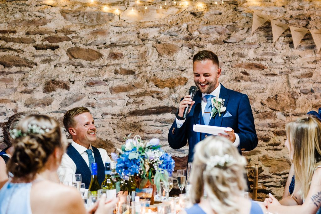 Groom gives his speech in stone barn.