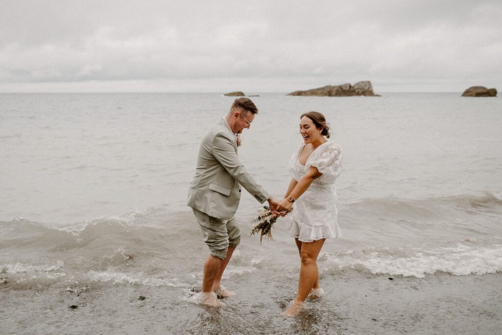 Newlyweds paddle in sea at Tunnels Beaches, Devon.