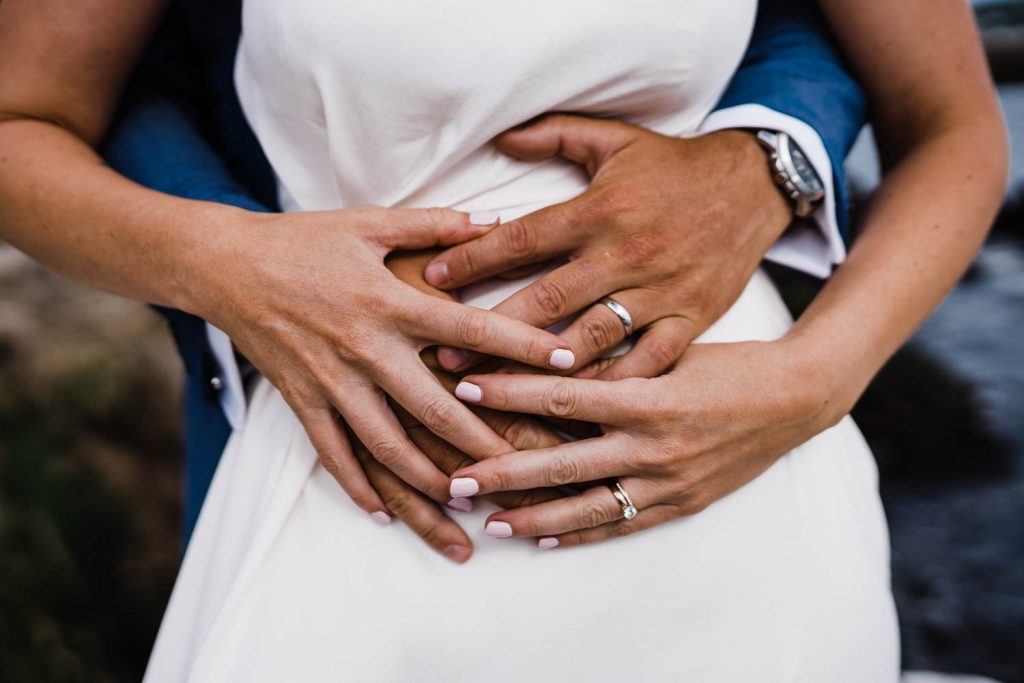 Close-up shot of bride and groom's hands and wedding rings.