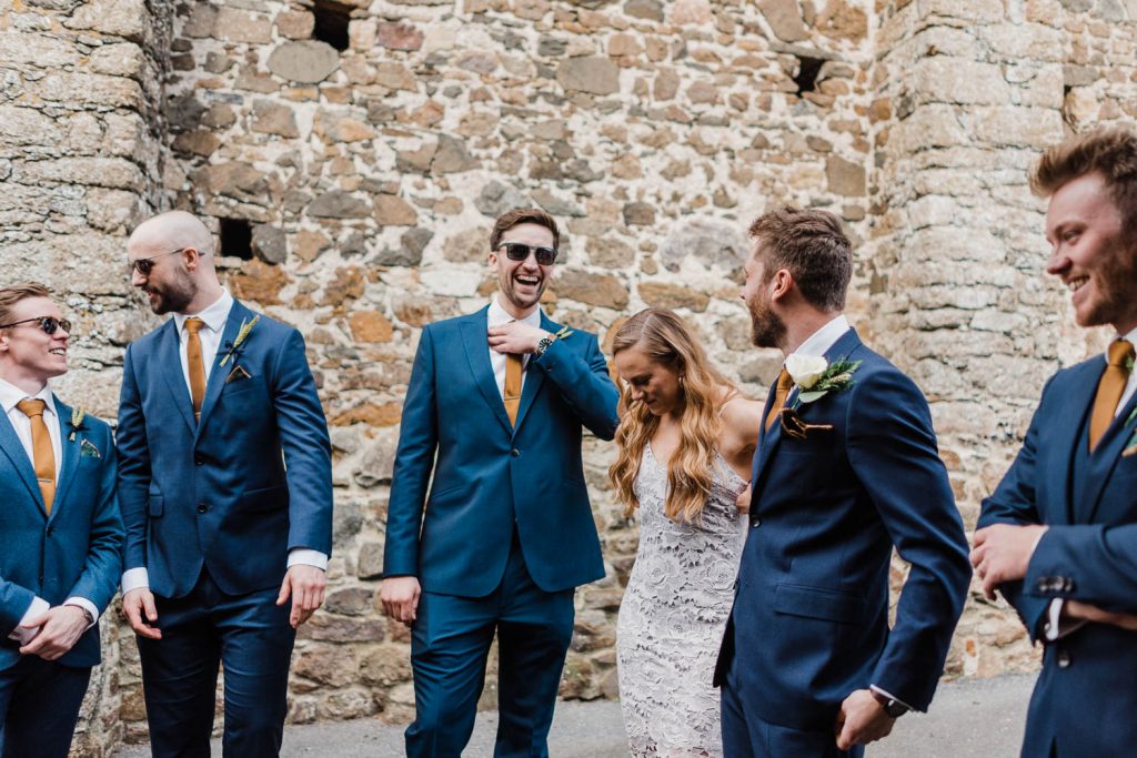 the groom laughs with his groomsmen outside The Great Barn Devon.