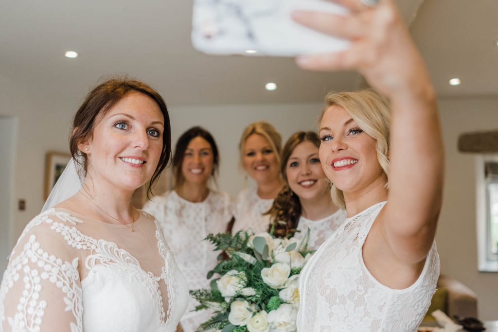 bride and bridesmaids take selfie.