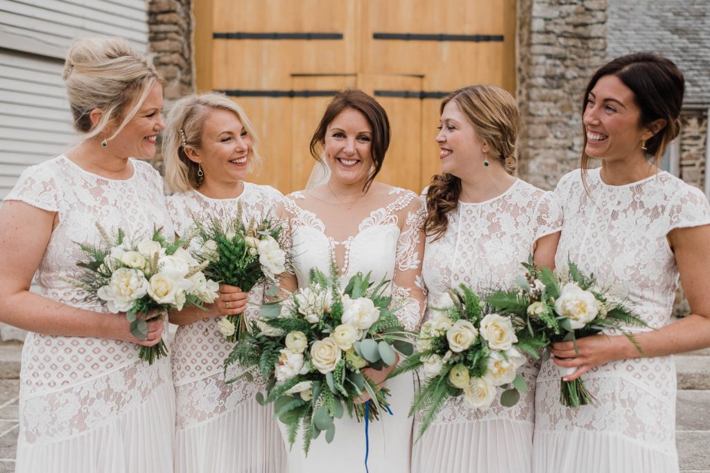 Bride and bridesmaids pose for photo outside the Great Barn Devon.