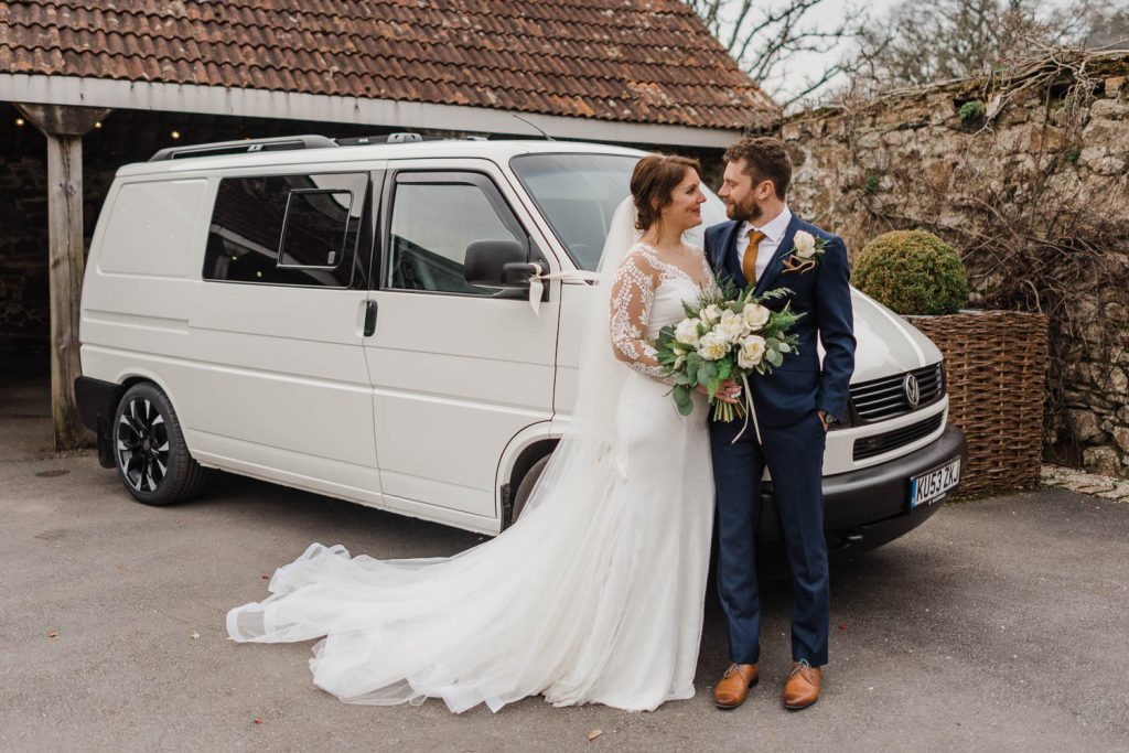 Bride & groom pose in front of their van.