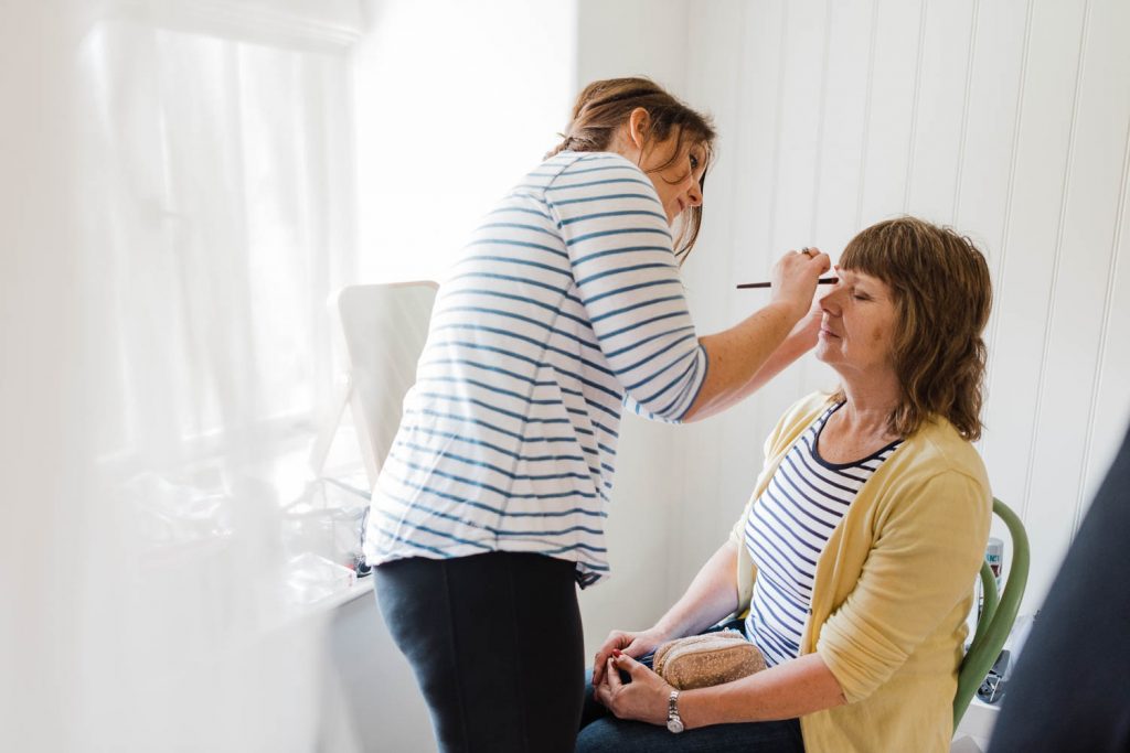 The bride applies makeup to her mother-in-law to be.