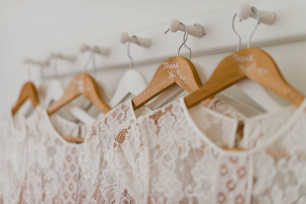 Bridesmaids dresses hang on clothes hangers, featuring the words 'Thank you!'