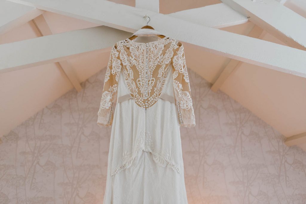 The brides dress hangs from beams on the morning of the wedding day.