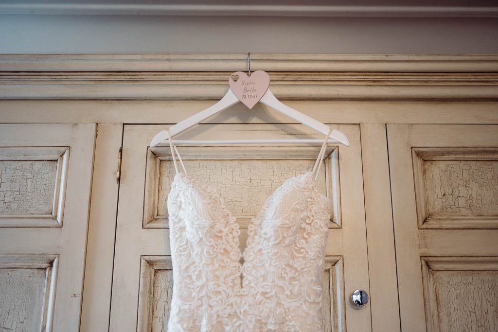 Bride's dress hangs on personalised hanger.