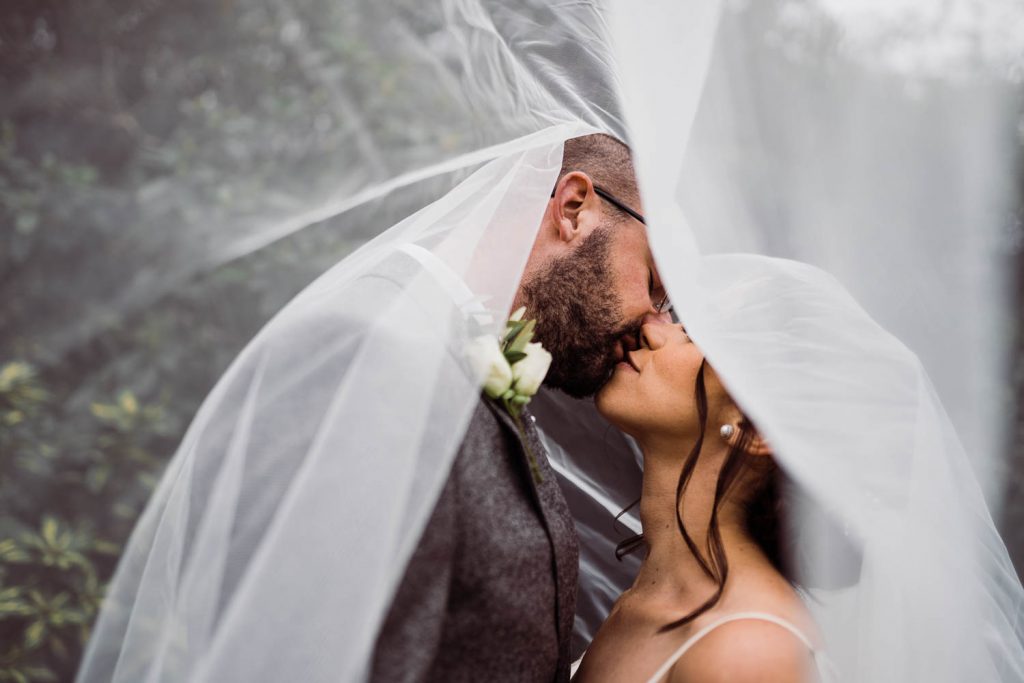 Bride and groom kiss under the bride's veil.