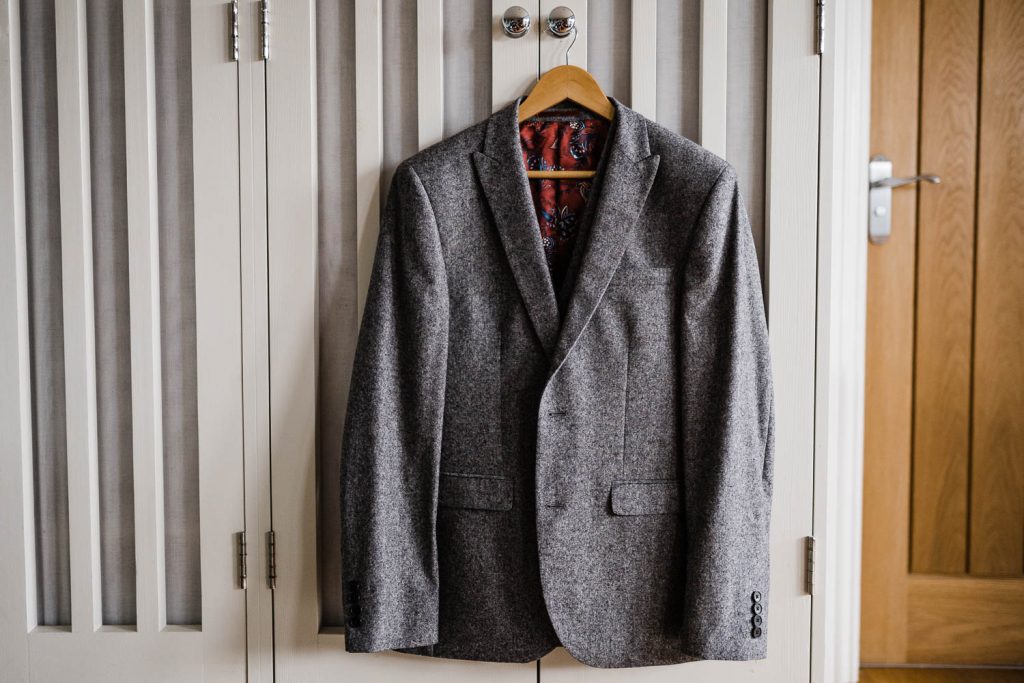 The groom's suit jacket hangs on the wardrobe.