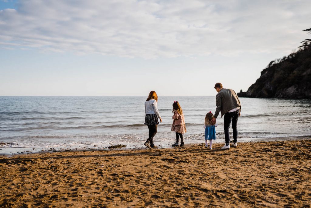 Family of four stand facing the sea at Mothecombe Beach.