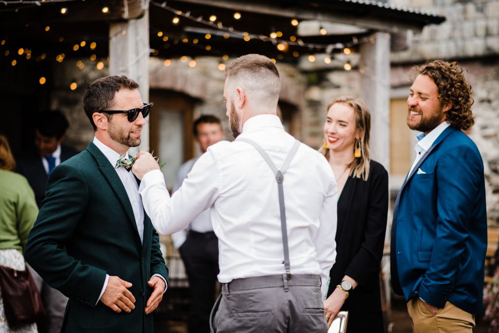 groomsmen adjusts groom's bowtie