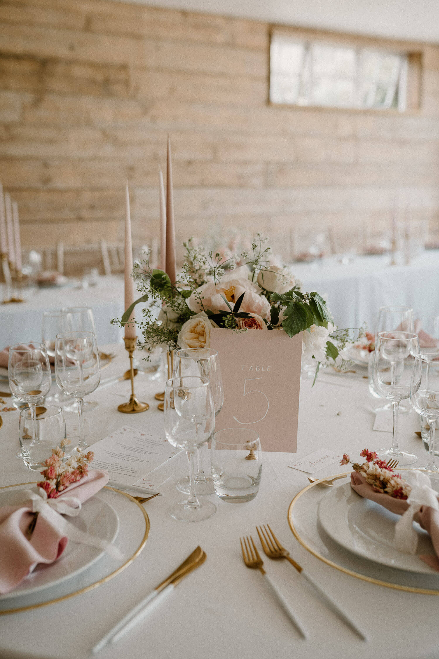 Beautifully styled converted barn reception space featuring a luxe colour scheme of pink and gold, stunning floral arrangements and glinting candlesticks.