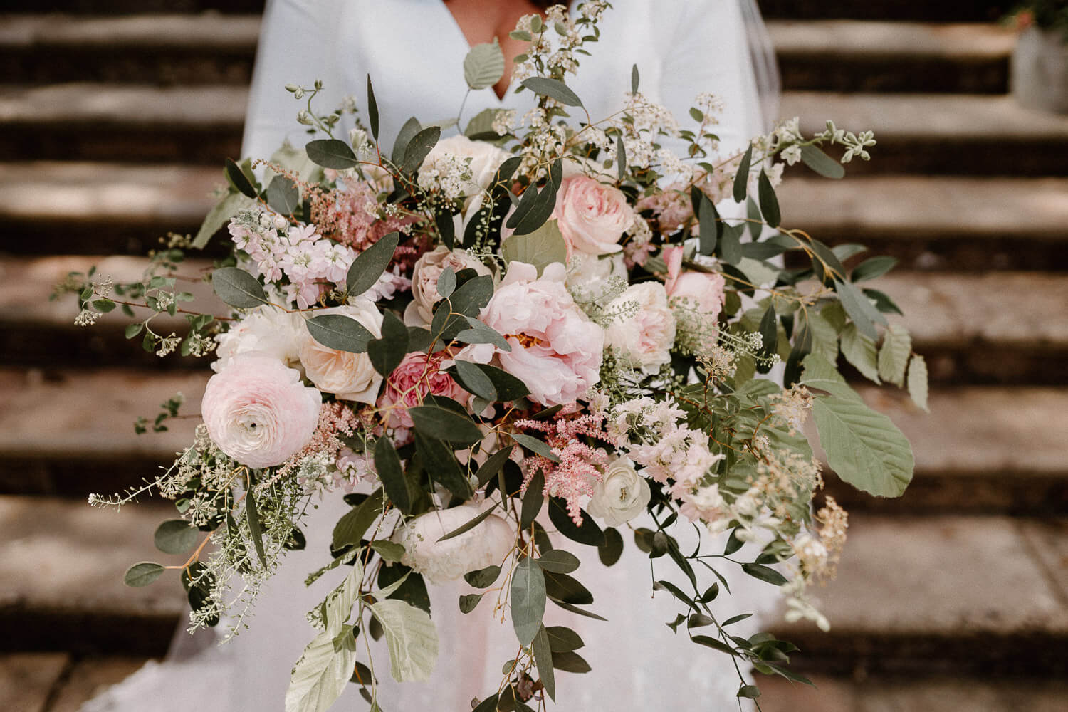 A close up view of a beautiful large bridal bouquet featuring blush pinks and eucalyptus.