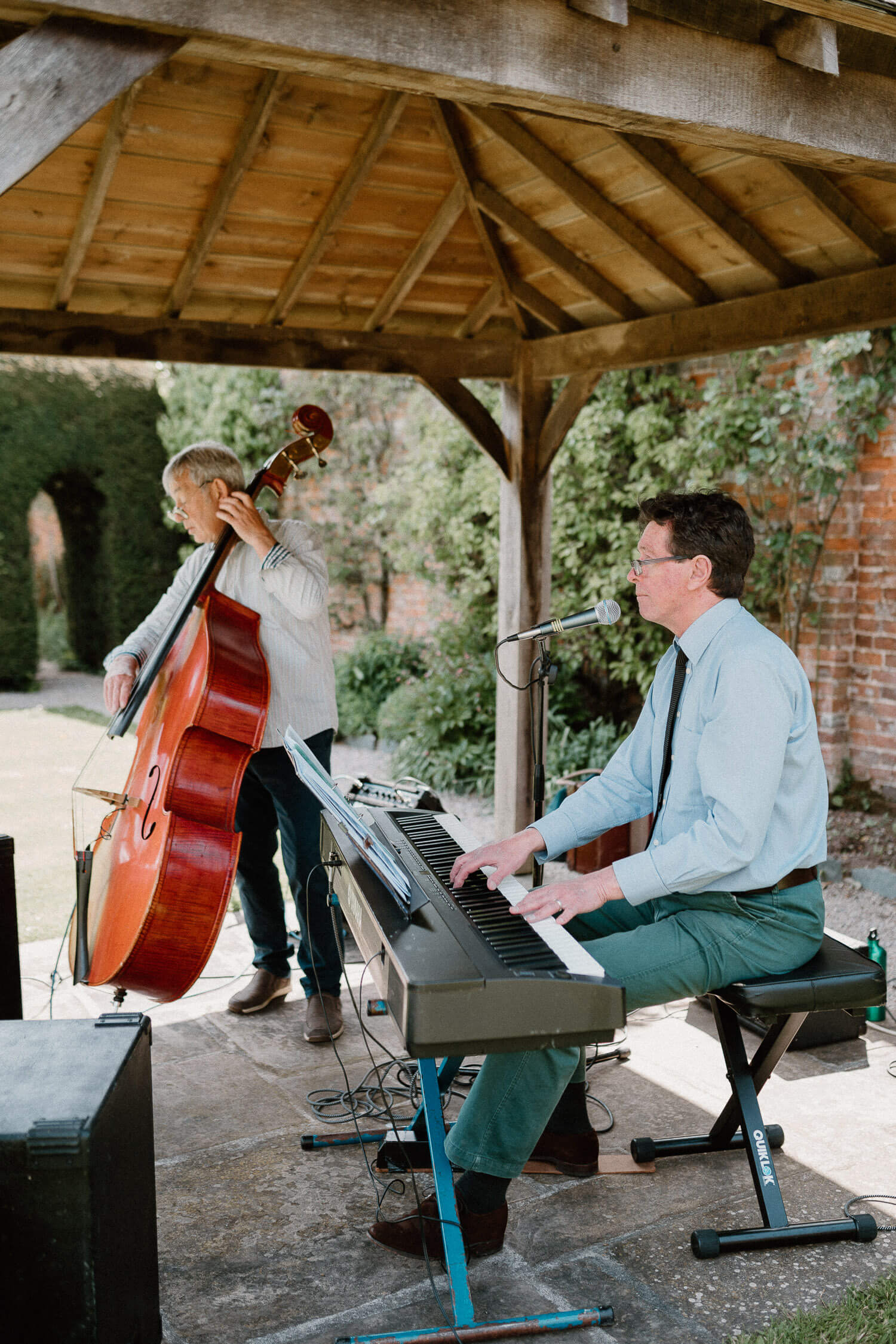Musicians play the double bass and keyboard during reception drinks in the walled garden at Kingston Estate.