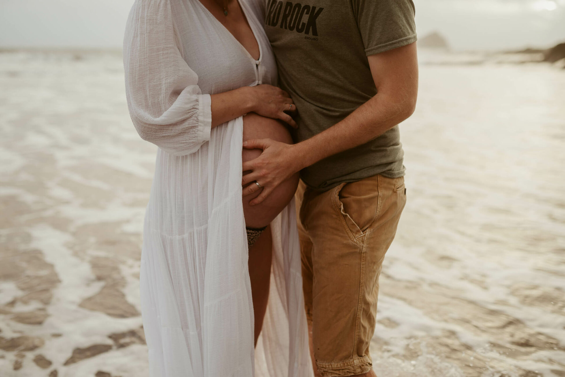 couple embrace during beach maternity photo session