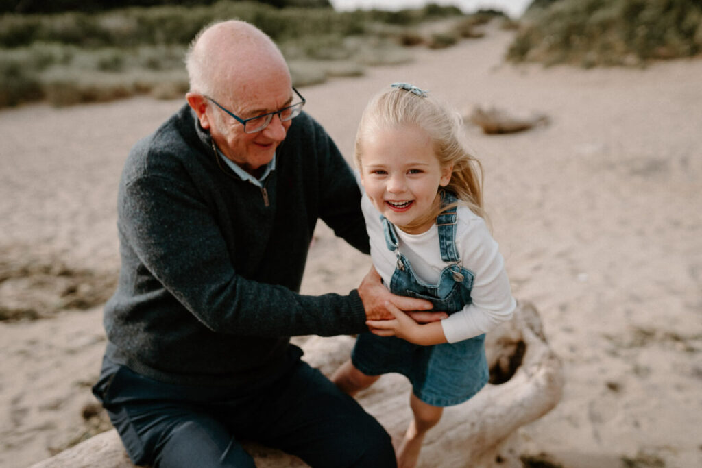 Grandfather and granddaughter play on the beach