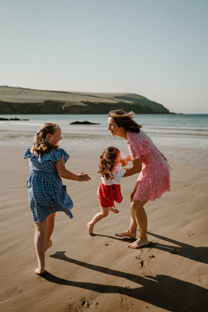 Mother and two daughters play on beach.