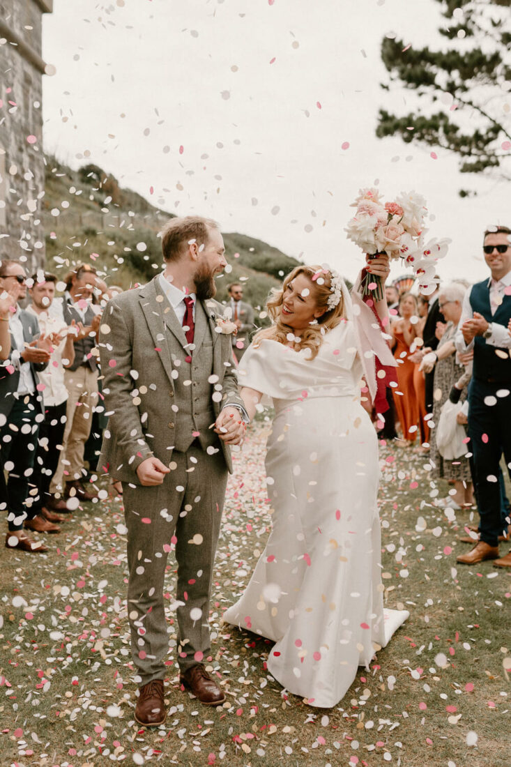 Bride and groom are showered with confetti at Polhawn Fort, Cornwall.