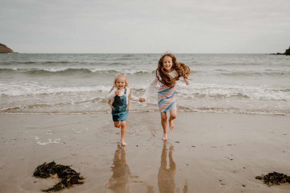 sisters run on the beach during family photography session