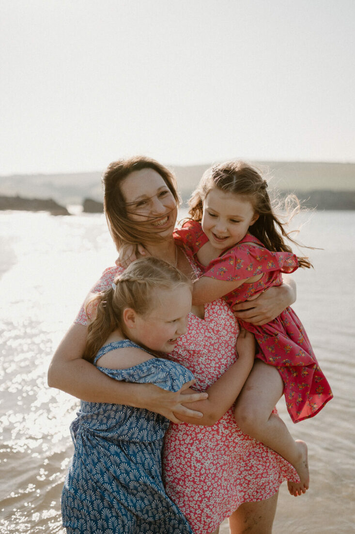 mother and two daughters hugging on Devon beach.